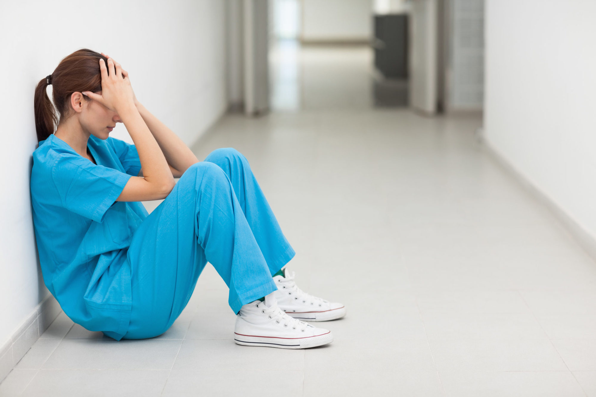 Nurse sitting in a corridor while holding her head - Patient Safety ...