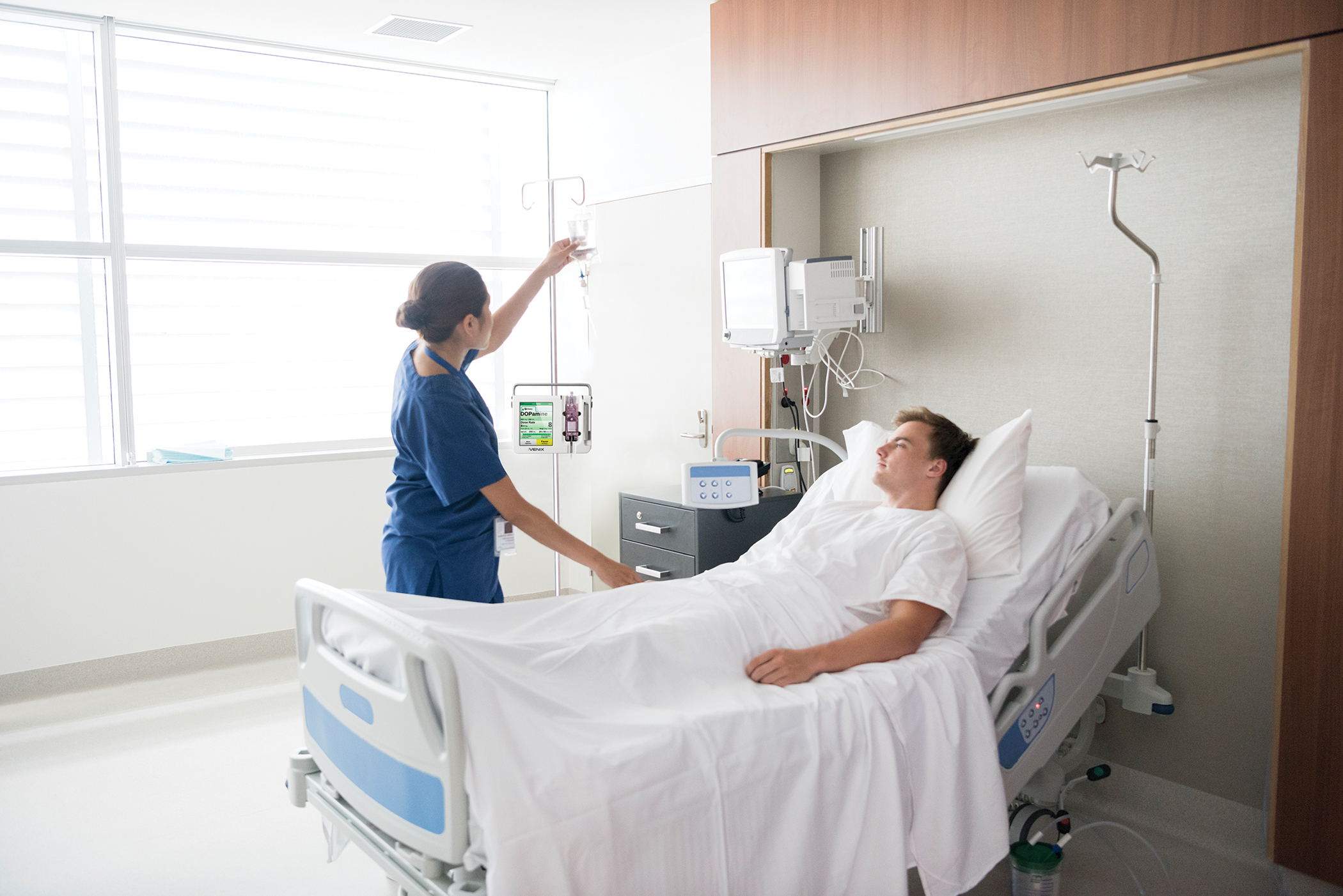 Female nurse tending to male patient in hospital bed - Patient Safety &  Quality Healthcare